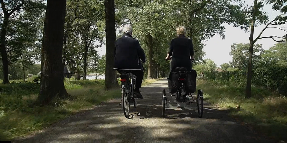 Twee fietsers van achteren, eentje met een driewieler